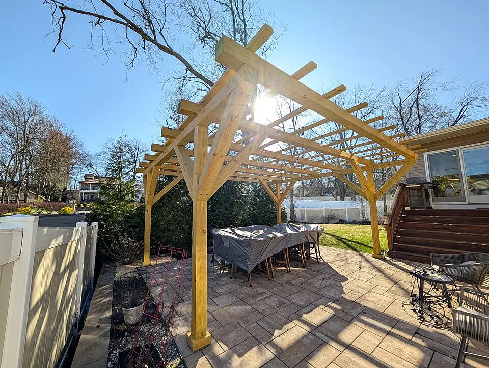 New wood pergola over a backyard patio with a dining table