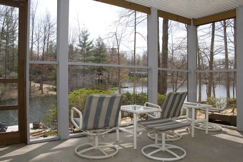 Screened porch with chairs overlooking water